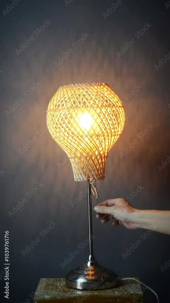 The standing lamp table lamp is turned on and off with a hand switch with a yellow light bulb on a gray and dark background Potrait