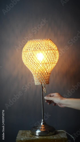 The standing lamp table lamp is turned on and off with a hand switch with a yellow light bulb on a gray and dark background Potrait