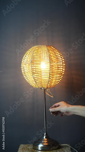 The standing lamp table lamp is turned on and off with a hand switch with a yellow light bulb on a gray and dark background Potrait