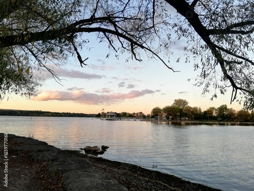 Low-angle view of a lake in a park in Ontario, Canada, with trees and a booth in the background. photo