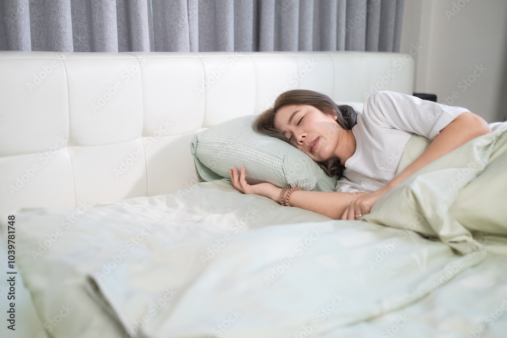A woman peacefully lying on a bed, covered in a white blanket, with her hands gently resting on her stomach. The serene setting highlights a quiet moment of relaxation in a modern bedroom. A woman peacefully lying on a bed, covered in a white blanket, with her hands gently resting on her stomach. The serene setting highlights a quiet moment of relaxation in a modern bedroom.