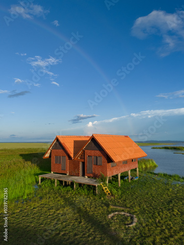 A pair of red abandoned houses against the rainbow at Thale Noi Lake, a famous tourist attraction in Phatthalung Province, Thailand photo