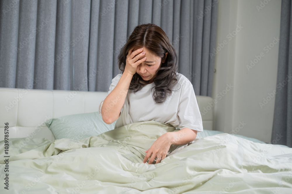 A woman lying in bed with her hand resting on her forehead, visibly uncomfortable due to a headache while checking for a fever. The soft bedding contrasts with the signs of unease, portraying a moment A woman lying in bed with her hand resting on her forehead, visibly uncomfortable due to a headache while checking for a fever. The soft bedding contrasts with the signs of unease, portraying a moment