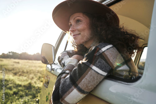 Woman Leaning Against Vintage Camper Van at Sunset photo