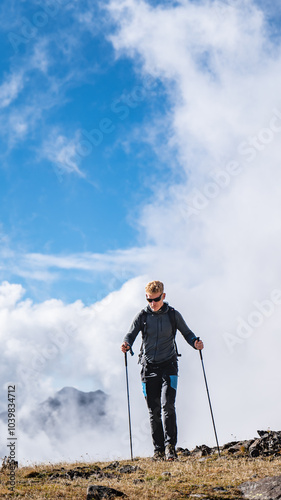 A man hiking in high mountains with clouds around