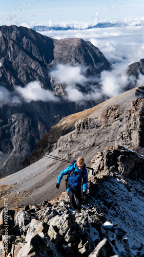 A man climbing a mountain ridge in the Alps