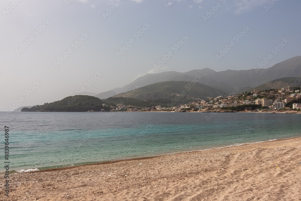 Panoramic view of the picturesque coastline of coastal tourist town Himare, Vlore, Albania. Sand beach Potami with scenic vistas of majestic mountains of Karaburun-Sazan Marine Park. Summer vacation