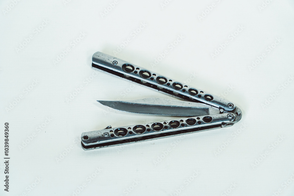 Partially open silver balisong or butterfly knife isolated on white background. Close-up of a sharp balisong knife or butterfly knife in various positions on a white background Partially open silver balisong or butterfly knife isolated on white background. Close-up of a sharp balisong knife or butterfly knife in various positions on a white background