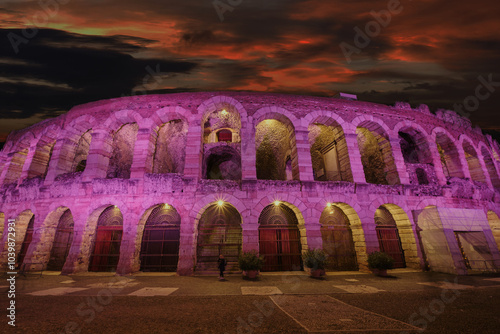 Arena di Verona in Italy, close-up in fuchsia against a pink sunset sky with clouds, evening shot at sunset.