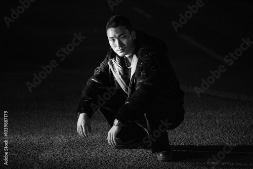 Obraz na płótnie A young Korean man is squatting. Black and white photo w salonie