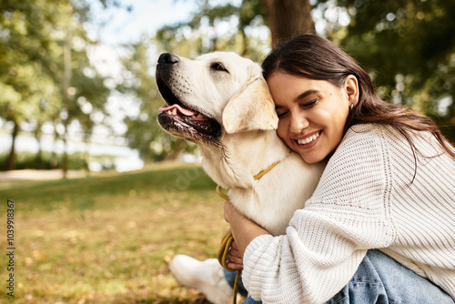 In the park, a young woman enjoys a heartwarming moment with her dog amidst autumn leaves. photo