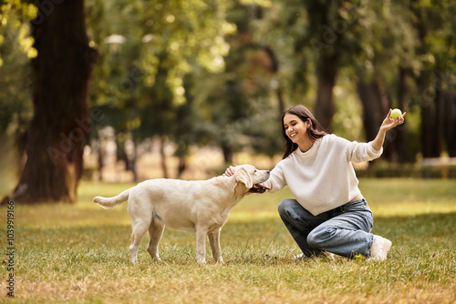 A young woman dressed in cozy autumn attire enjoys a playful interaction with her dog in the park.