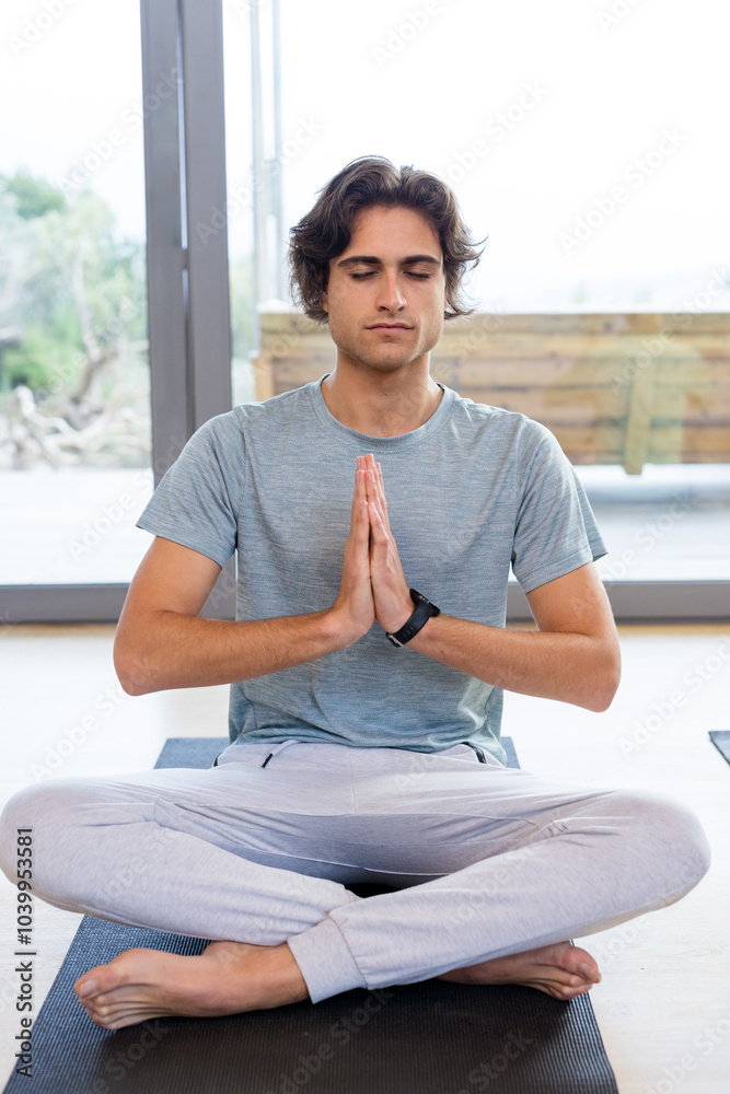 Man meditating on yoga mat at home, practicing mindfulness and relaxation Man meditating on yoga mat at home, practicing mindfulness and relaxation