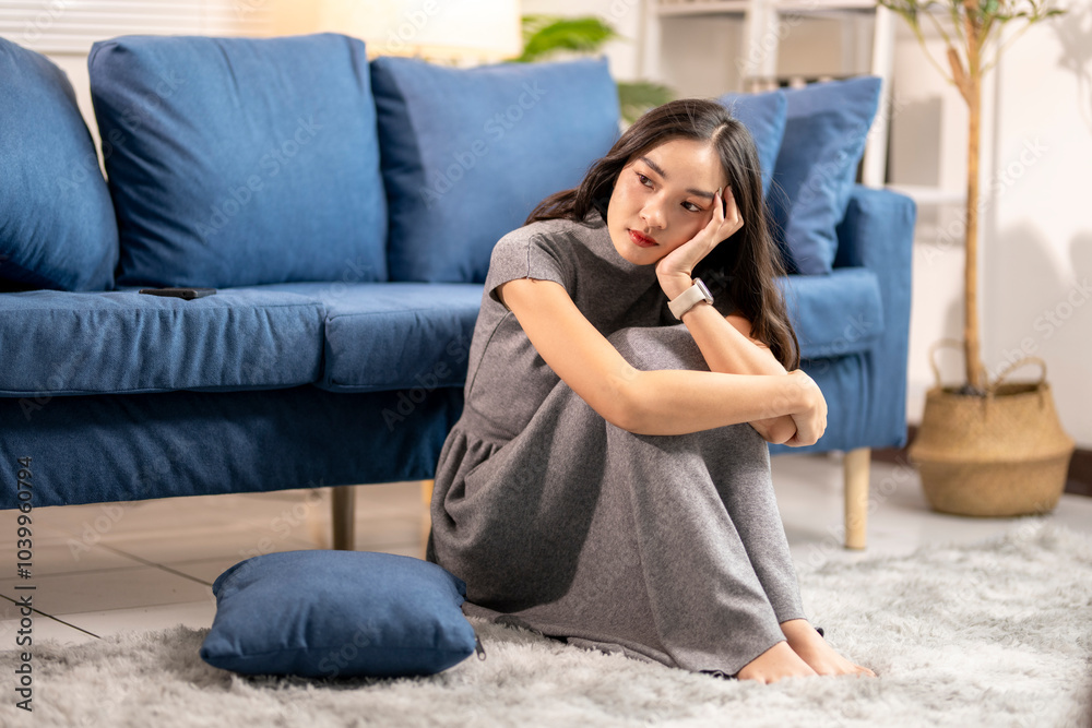 Obraz premium Young woman feeling sad and depressed while sitting on the floor in the living room