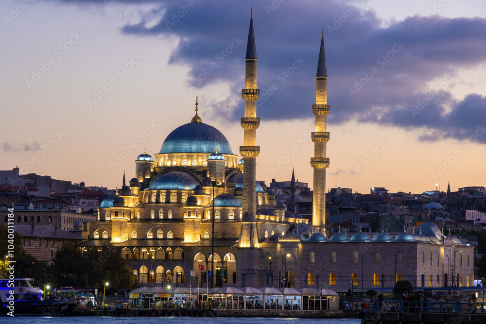 Naklejka premium Yeni Cami Mosque in Istanbul, Turkey, illuminated by lights at dusk
