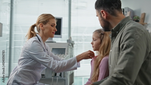 Smiling doctor measuring temperature in examination room. Father visiting clinic