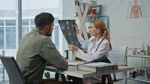 Doctor consulting patient x-ray in clinic. Medical professional explaining photo