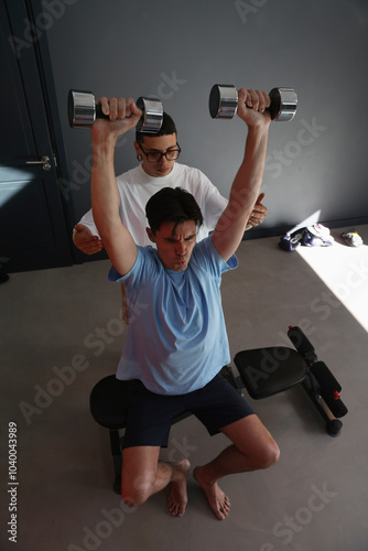 Person assisting man during strength exercise