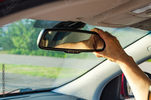 Woman adjusting rear view mirror inside car before driving.