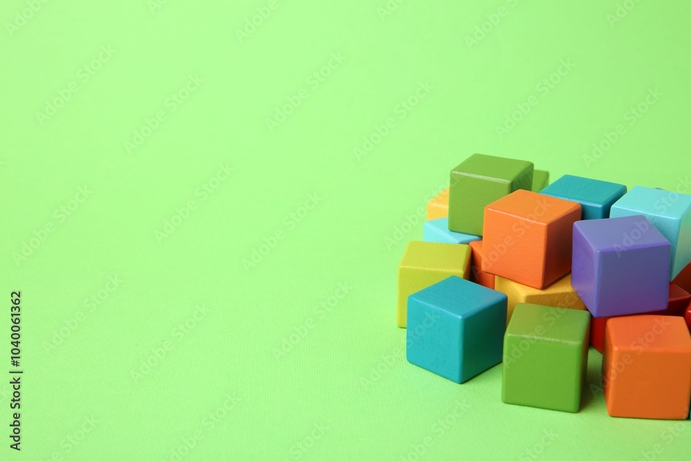 Many wooden colorful cubes on green background, space for text Many wooden colorful cubes on green background, space for text