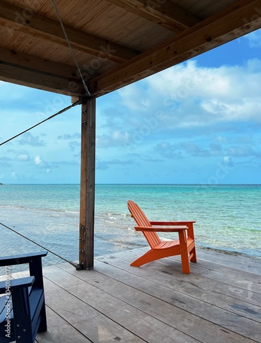 Red chair on dock overlooking the water in the Caribbean. 