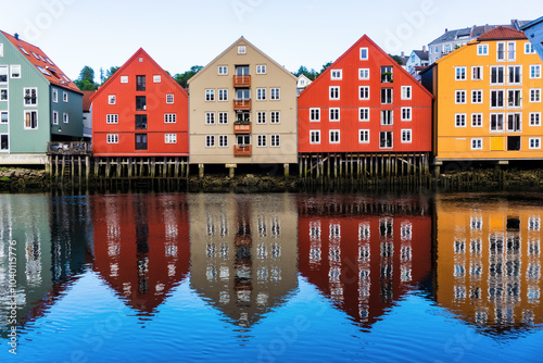 Embankment with beautifully colored old wooden warehouse, storage buildings and nordic houses in the center of norwegian city Trondheim-Nidaros reflect in the calm water of old harbour. Norway. photo