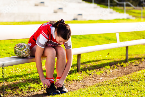 Young aboriginal footy player tying up laces on shoes before game photo