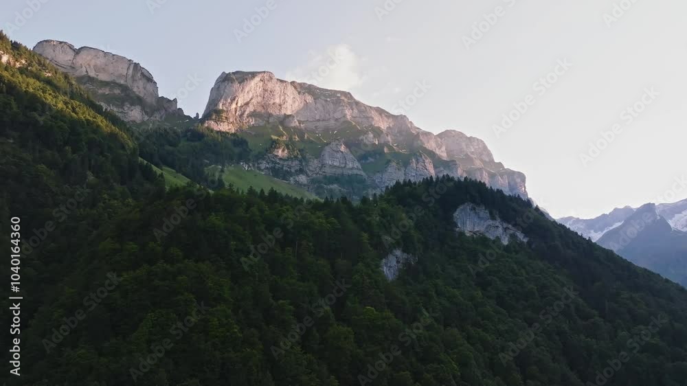 Drone video of the Swiss Alps at dusk, with the last light touching the mountain peaks. Drone move up.