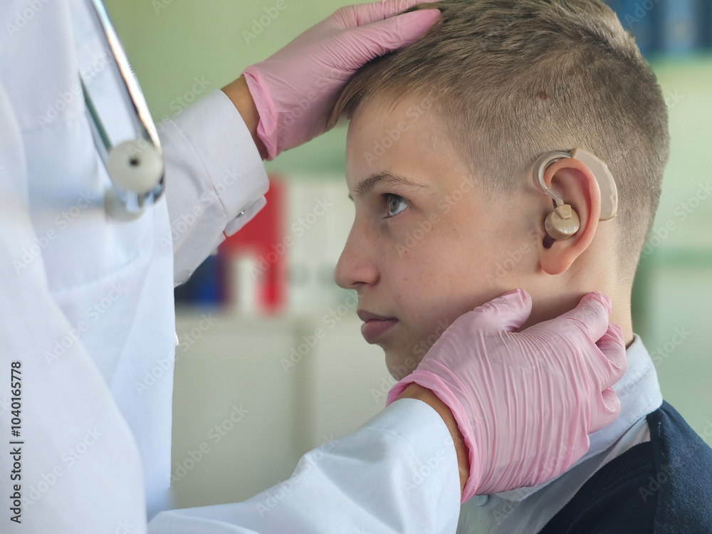 Fototapeta premium A pediatric audiologist fitting a young boy with a hearing aid in a medical office
