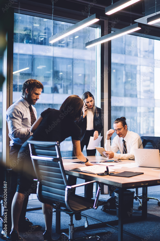 © BullRun - Cooperation process of professional male and female colleagues,business woman in formal suit communicate with operator via smartphone gadget while reading email from partners touch pad during teamwork