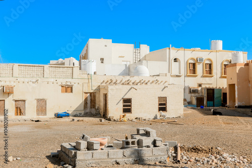 Exploring traditional architecture in Sur Oman under a clear blue sky with limestone buildings and local construction activity