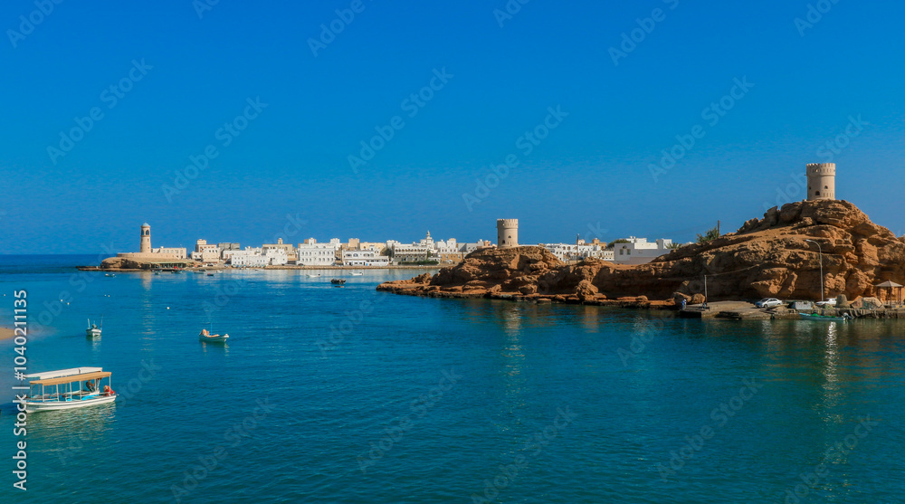 A serene view of Sur Oman showcasing traditional boats and stunning coastal architecture under a clear blue sky A serene view of Sur Oman showcasing traditional boats and stunning coastal architecture under a clear blue sky
