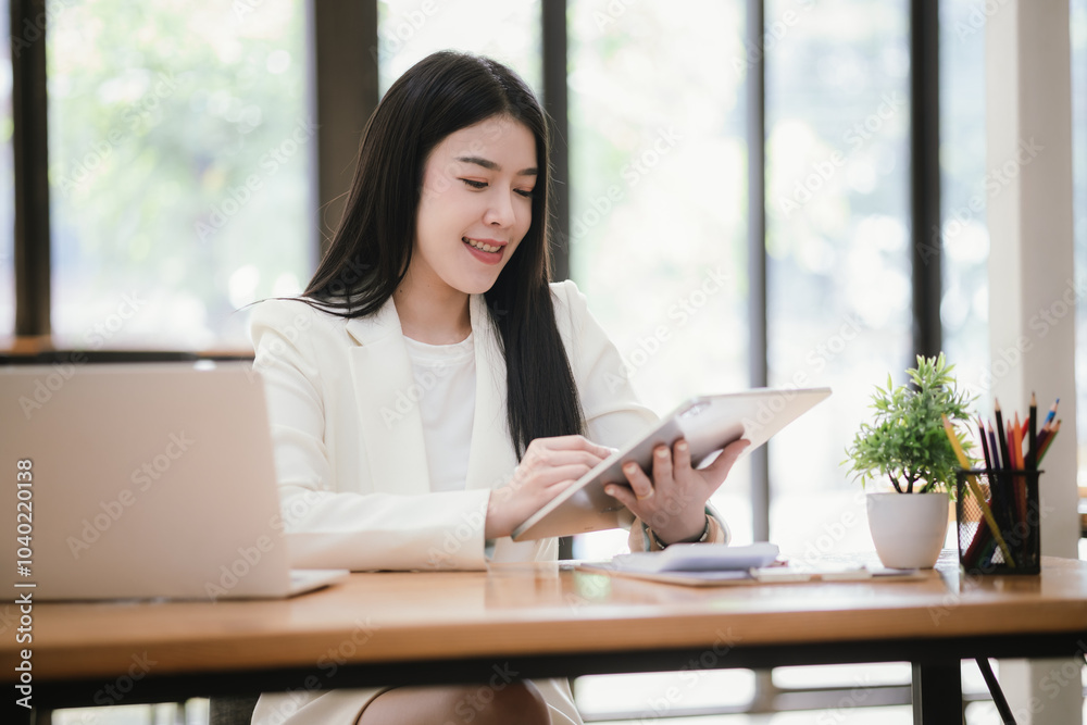Beautiful Asian businesswoman focused on reviewing documents in a modern office. Beautiful Asian businesswoman focused on reviewing documents in a modern office.