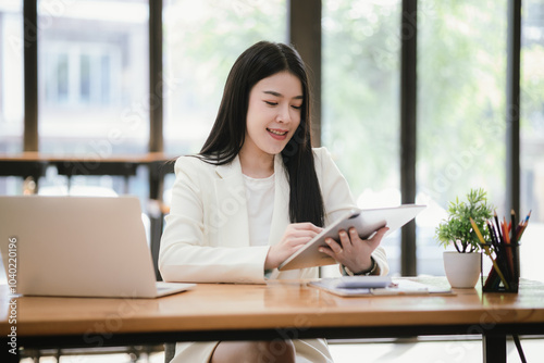 Beautiful Asian businesswoman focused on reviewing documents in a modern office.