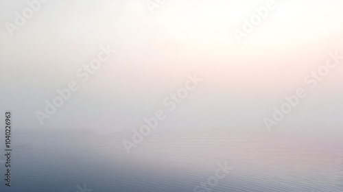 A serene early morning view of a calm lake enveloped in mist, reflecting soft sunlight and creating a tranquil atmosphere photo