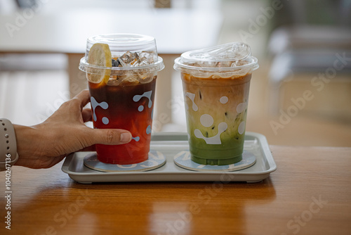 Tablou pe pânză hand of woman holding a take-out iced tea honey lemon on table at coffee shop