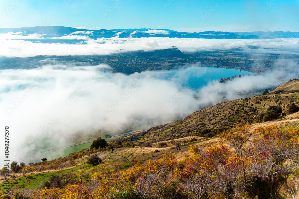 Obraz premium Scenic foggy mountain view from summit of Roys Peak and Lake Wanaka in autumn at New Zealand