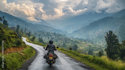 A man in a helmet riding a motorcycle up a winding road, the hilltop nearly in view, the valley below stretching out with scattered villages and farmlands, the sky filled with dramatic clouds,