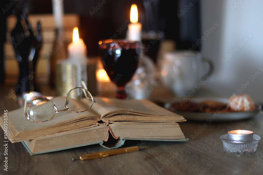Books, lit candles, red wine, snacks and various deocration on the table. Dark academia or Halloween concept. Selective focus. Books, lit candles, red wine, snacks and various deocration on the table. Dark academia or Halloween concept. Selective focus.