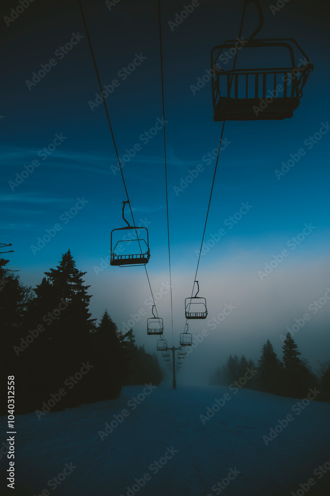 Chairlift at a ski and snowboard resort during winter with fresh white snow, blue sky and misty fog. Killington, Vermont, New England, USA. Chairlift at a ski and snowboard resort during winter with fresh white snow, blue sky and misty fog. Killington, Vermont, New England, USA.