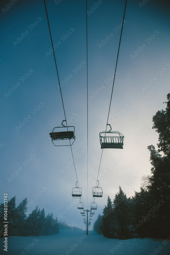 Chairlift at a ski and snowboard resort during winter with fresh white snow, blue sky and misty fog. Killington, Vermont, New England, USA. Chairlift at a ski and snowboard resort during winter with fresh white snow, blue sky and misty fog. Killington, Vermont, New England, USA.
