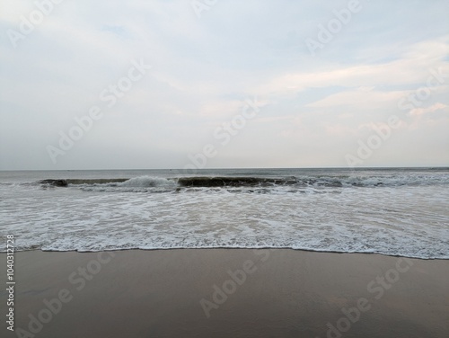 A serene evening at Rushikonda Beach, in Andhra Pradesh, India, with soft golden hues from the setting sun reflecting on the calm, blue waters. photo