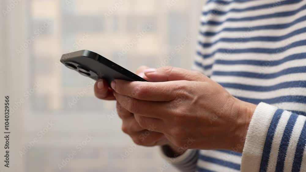 A close-up of hands holding a smartphone at home or work. Woman using smartphone pressing fingerers, reading social media internet, typing text or shopping online.