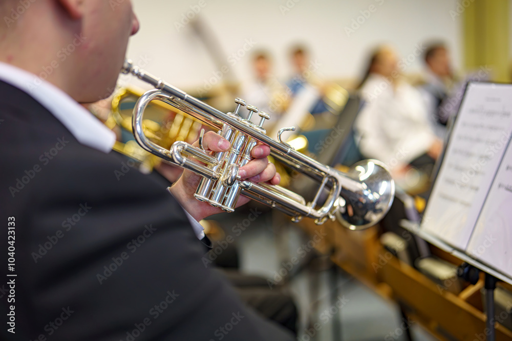 Obraz premium A musician in an orchestra plays a musical composition on a trumpet in an orchestra.