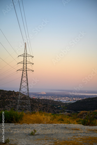 This is a shot of a high-voltage electric transmission tower, also known as an electricity overhead line pylon or lines, at sunset