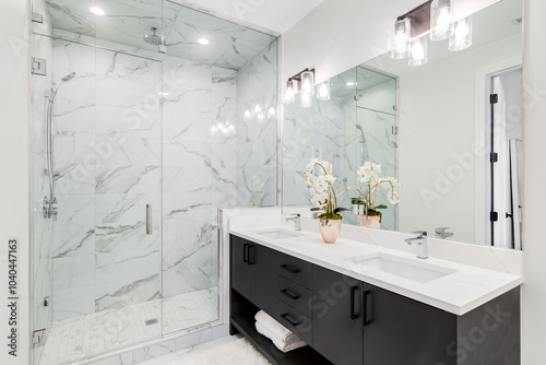 A modern bathroom with a dark cabinet, white marble countertop, marble tile walk-in shower, and chrome faucets. No brands or labels. photo