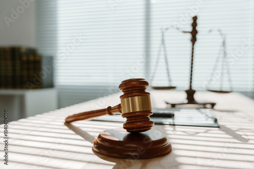 Polished wooden gavel is lying on a sound block, casting a long shadow on a sunlit desk in a law office photo