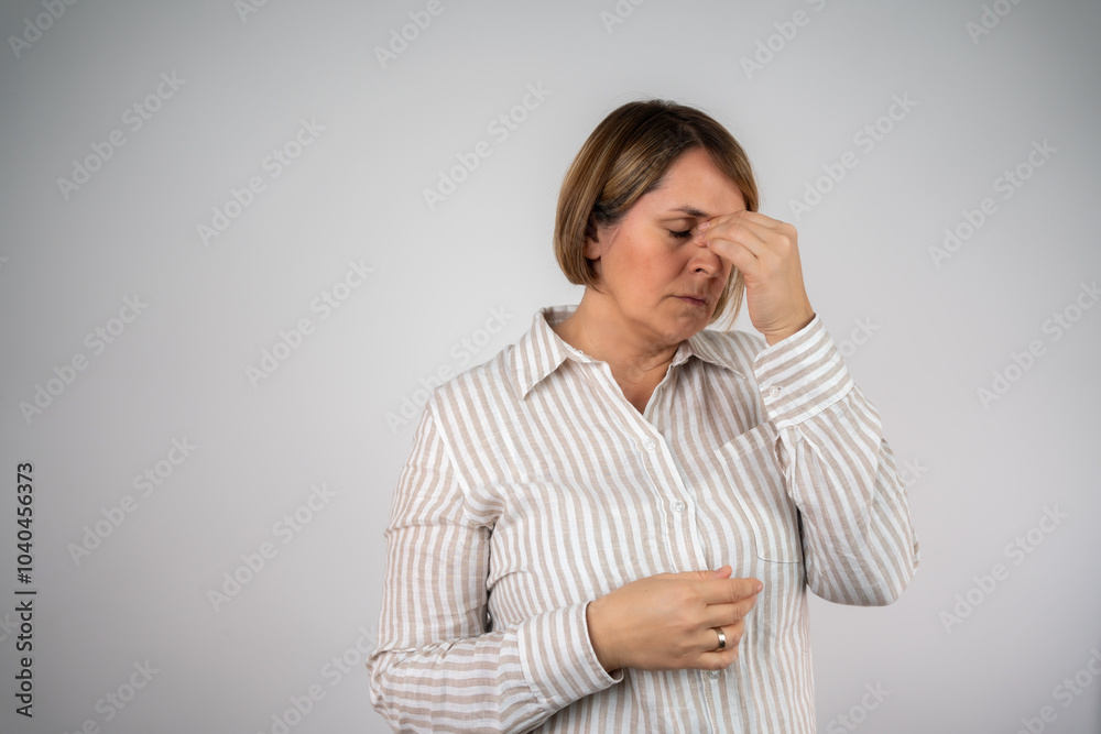The stressed mature woman. Mature pretty woman over isolated background with headache. woman experiencing a headache, holding her forehead in discomfort isolated on white background The stressed mature woman. Mature pretty woman over isolated background with headache. woman experiencing a headache, holding her forehead in discomfort isolated on white background