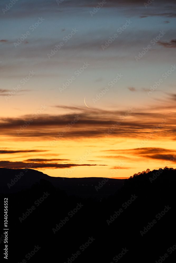 Luna menguante tras las nubes, al alba con de siluetas de montañas Luna menguante tras las nubes, al alba con de siluetas de montañas