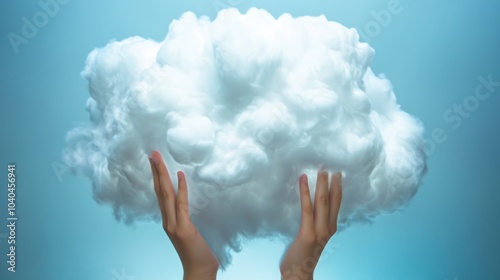 A pair of hands holds a fluffy white cloud against a serene blue background, symbolizing dreams and creativity.